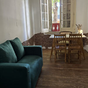 Espacio de Eirá con sillón verde y mesa de madera
